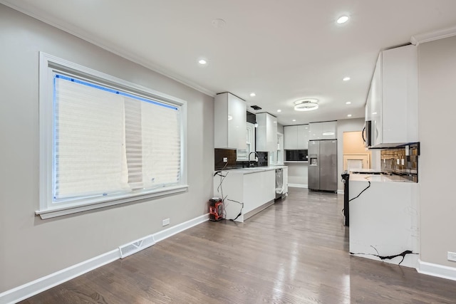 kitchen with backsplash, ornamental molding, stainless steel appliances, dark hardwood / wood-style floors, and white cabinetry