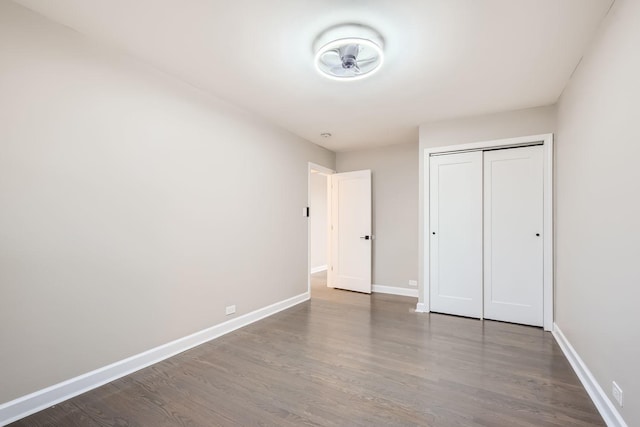 unfurnished bedroom with dark hardwood / wood-style floors and a closet