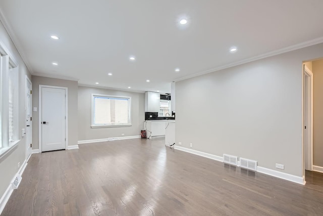 unfurnished living room with sink, hardwood / wood-style floors, and ornamental molding