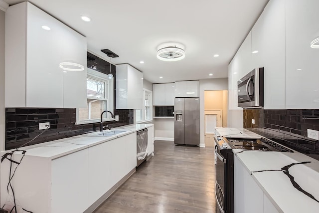 kitchen with decorative backsplash, stainless steel appliances, sink, hardwood / wood-style floors, and white cabinetry