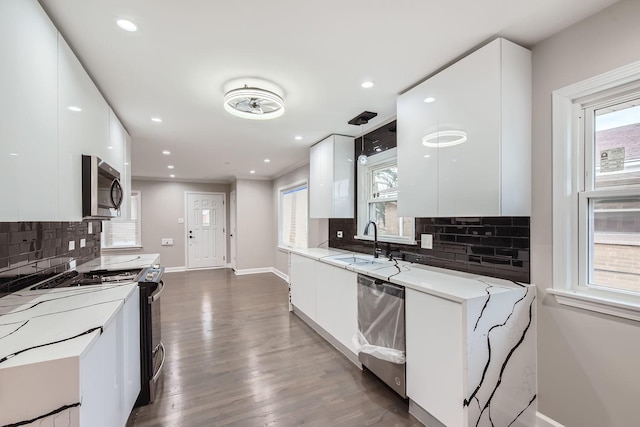 kitchen featuring white cabinetry, sink, dark wood-type flooring, stainless steel appliances, and pendant lighting