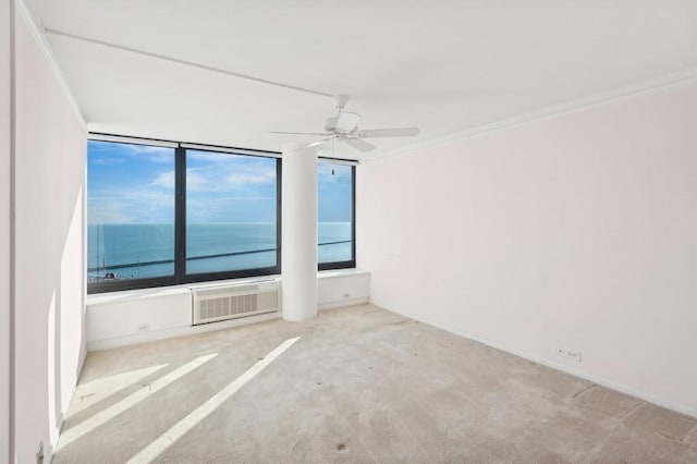 carpeted empty room with a water view, ceiling fan, and ornamental molding