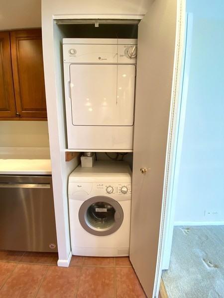 laundry room featuring light tile patterned floors and stacked washer / drying machine