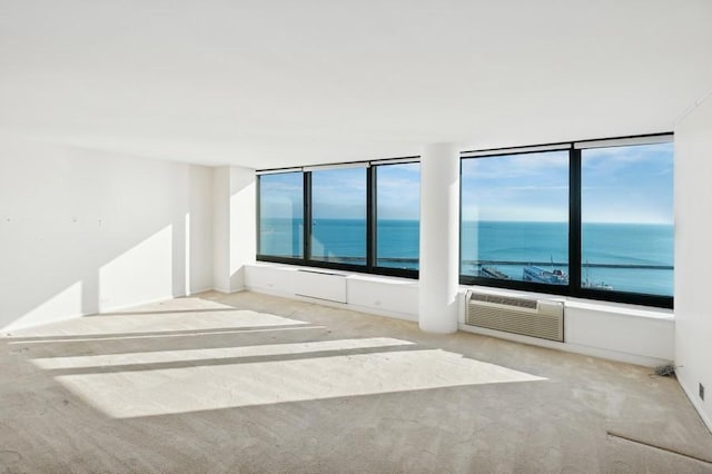 carpeted empty room featuring a wall mounted AC and a water view