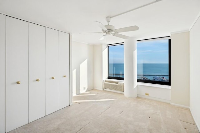 unfurnished bedroom with ceiling fan, a water view, ornamental molding, and light carpet