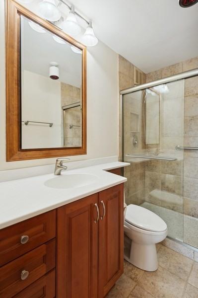 bathroom featuring walk in shower, tile patterned flooring, vanity, and toilet