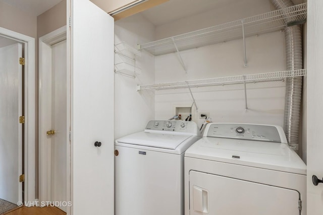 clothes washing area with washer and clothes dryer and hardwood / wood-style flooring