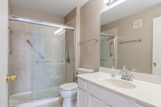 bathroom featuring tile patterned flooring, vanity, toilet, and a shower with shower door