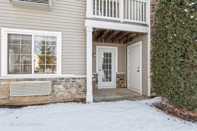 snow covered property entrance featuring a balcony