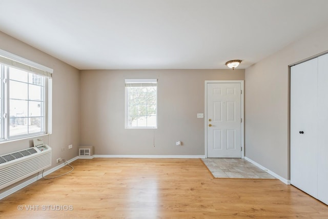 interior space with a wall mounted AC, a healthy amount of sunlight, and light wood-type flooring