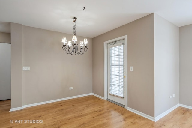 unfurnished room featuring wood-type flooring and an inviting chandelier