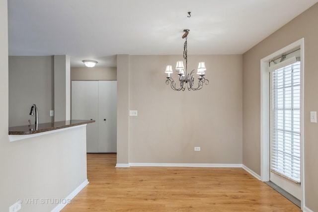 unfurnished dining area with a chandelier and light hardwood / wood-style floors