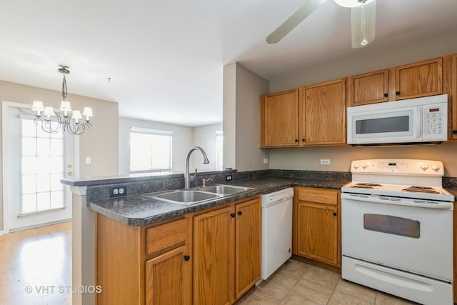 kitchen with white appliances, ceiling fan with notable chandelier, sink, hanging light fixtures, and kitchen peninsula