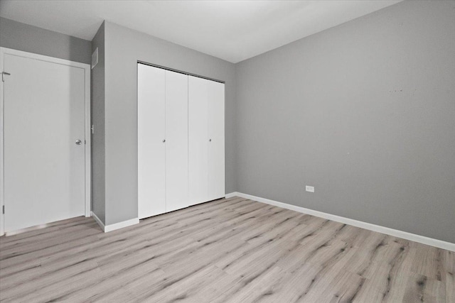 unfurnished bedroom featuring light wood-type flooring and a closet