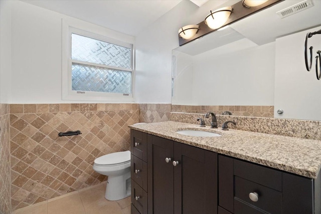 bathroom with tile patterned flooring, vanity, tile walls, and toilet