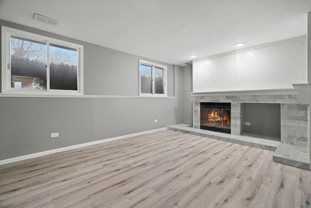 unfurnished living room with a stone fireplace and light hardwood / wood-style flooring