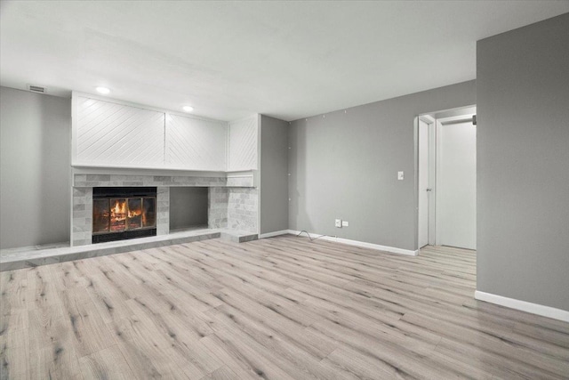 unfurnished living room with light wood-type flooring and a large fireplace