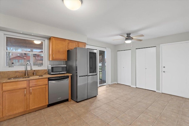 kitchen featuring light stone countertops, stainless steel appliances, ceiling fan, sink, and light tile patterned floors