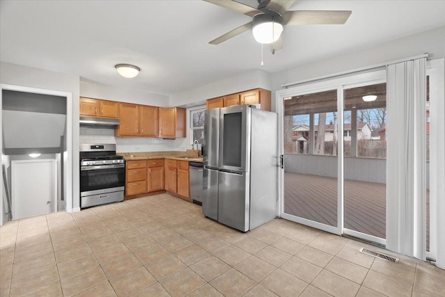 kitchen with appliances with stainless steel finishes, backsplash, ceiling fan, sink, and light tile patterned flooring