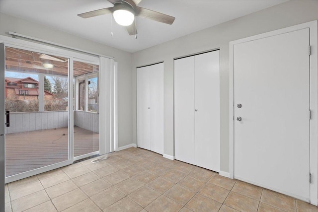 unfurnished bedroom featuring multiple closets, ceiling fan, and light tile patterned flooring