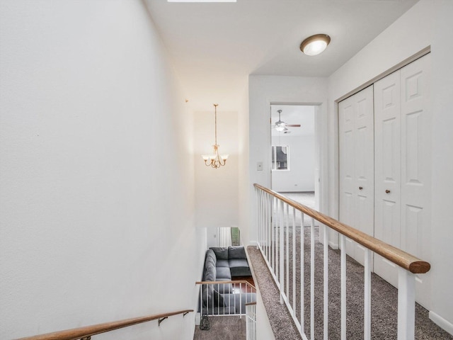 hallway with carpet and a notable chandelier