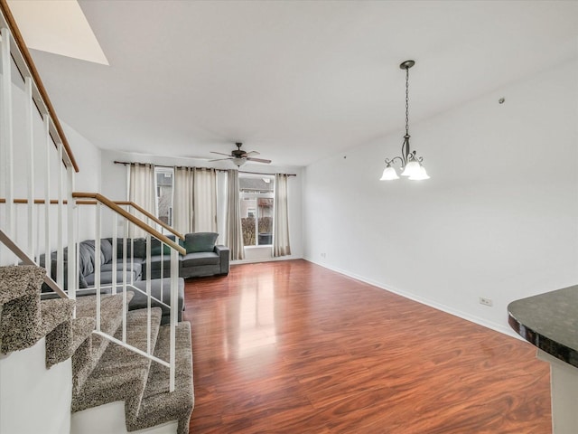 living room with ceiling fan with notable chandelier and dark wood-type flooring