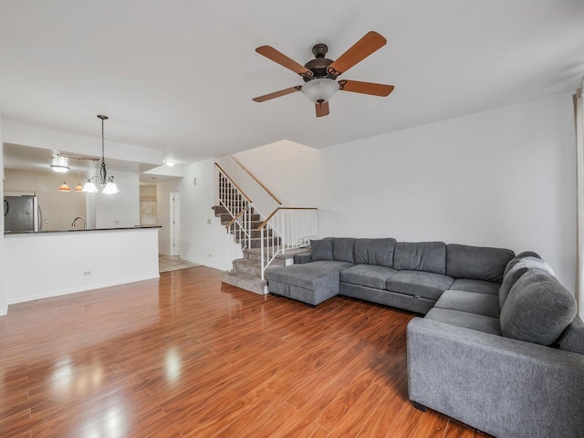 living room with ceiling fan with notable chandelier and hardwood / wood-style flooring