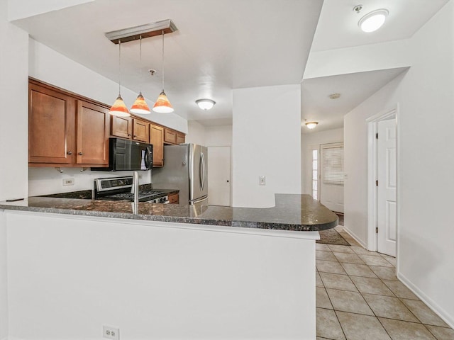 kitchen featuring kitchen peninsula, stainless steel appliances, light tile patterned floors, decorative light fixtures, and dark stone countertops