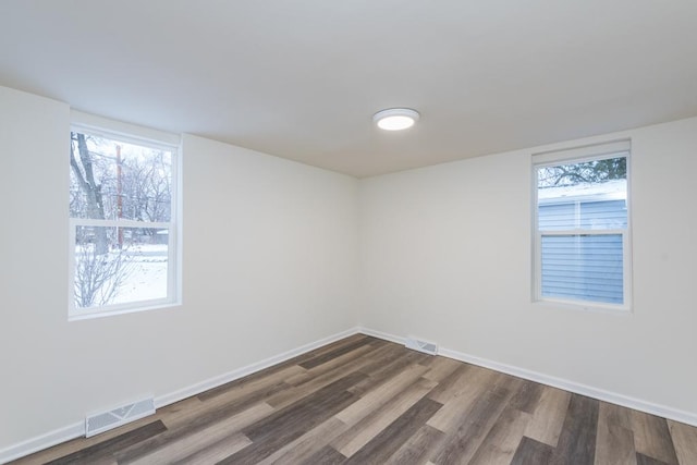 empty room featuring a healthy amount of sunlight and dark hardwood / wood-style floors