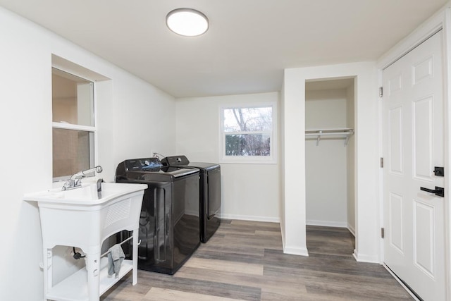 clothes washing area with sink, washer and clothes dryer, and hardwood / wood-style flooring