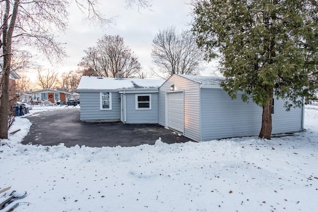 snow covered rear of property featuring an outdoor structure