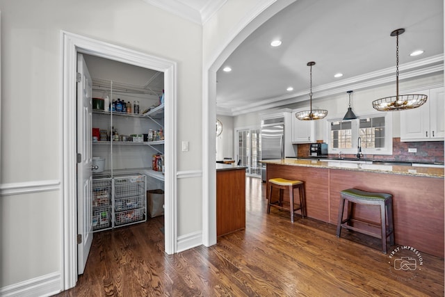 kitchen with light stone counters, a breakfast bar, white cabinets, and decorative light fixtures