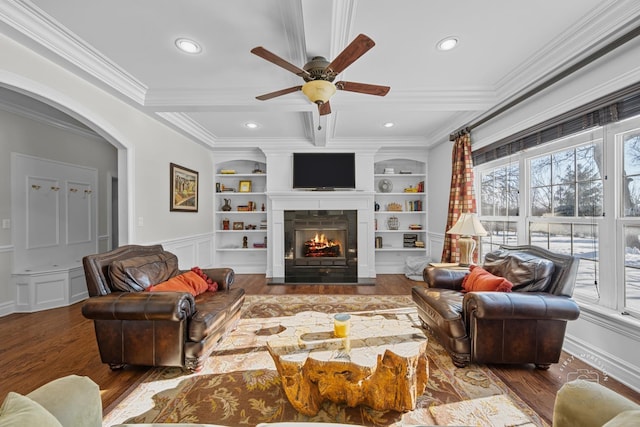 living area with built in features, dark wood finished floors, beamed ceiling, and a lit fireplace