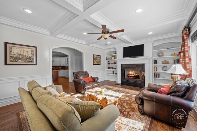 living area featuring built in shelves, arched walkways, coffered ceiling, and beamed ceiling