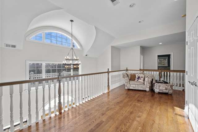 hallway featuring vaulted ceiling, visible vents, a notable chandelier, and wood finished floors