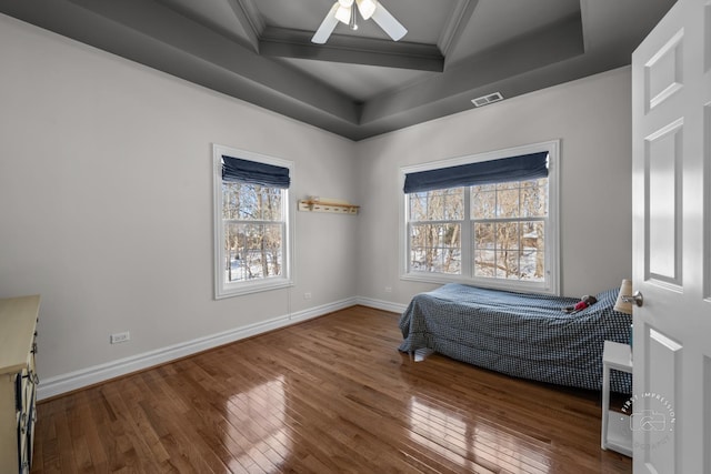 bedroom featuring ornamental molding, hardwood / wood-style floors, and a raised ceiling