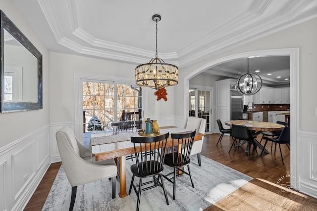 dining area featuring an inviting chandelier, arched walkways, and dark wood-style flooring