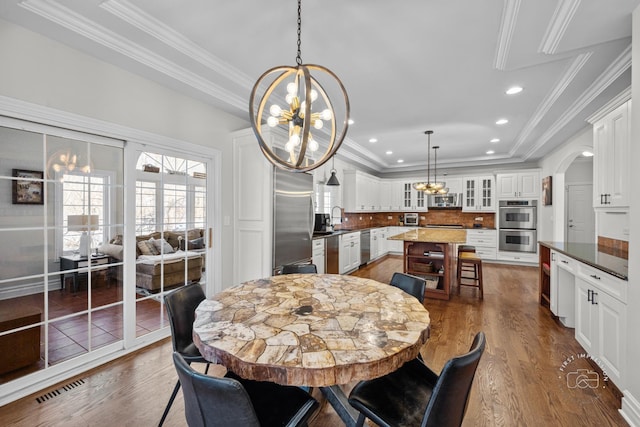 dining area featuring dark wood-style flooring, visible vents, and a notable chandelier