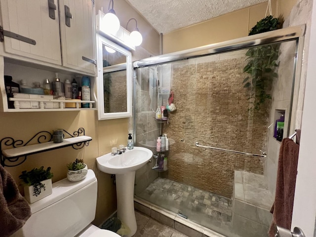 bathroom featuring toilet, a shower with shower door, and a textured ceiling