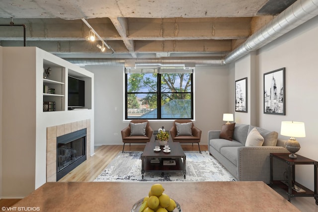 living room featuring a tiled fireplace and light hardwood / wood-style floors