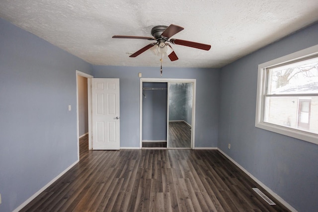 unfurnished bedroom featuring a textured ceiling, ceiling fan, dark wood-type flooring, and a closet