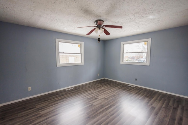 spare room with a textured ceiling, a wealth of natural light, ceiling fan, and dark hardwood / wood-style floors