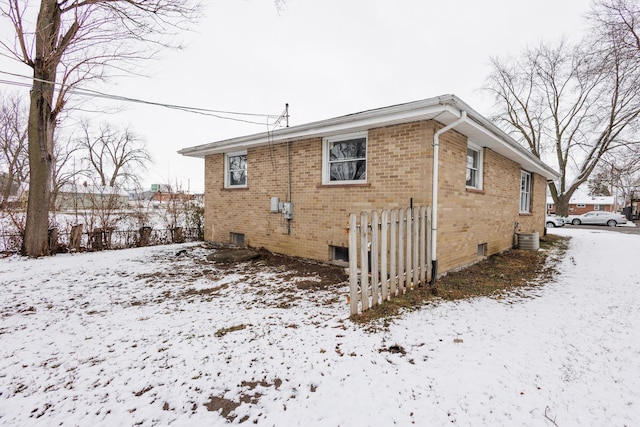 snow covered house featuring central AC