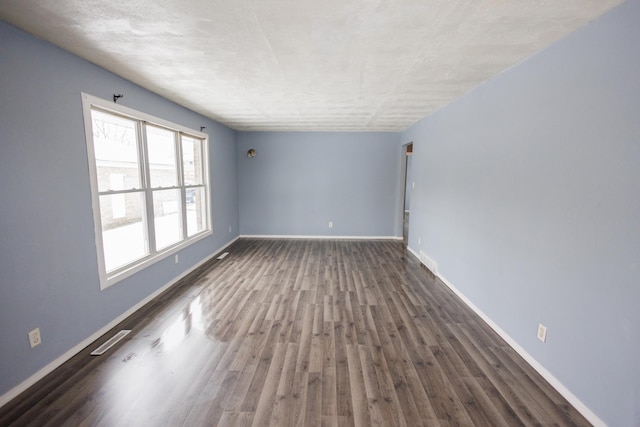 unfurnished room with dark wood-type flooring and a textured ceiling