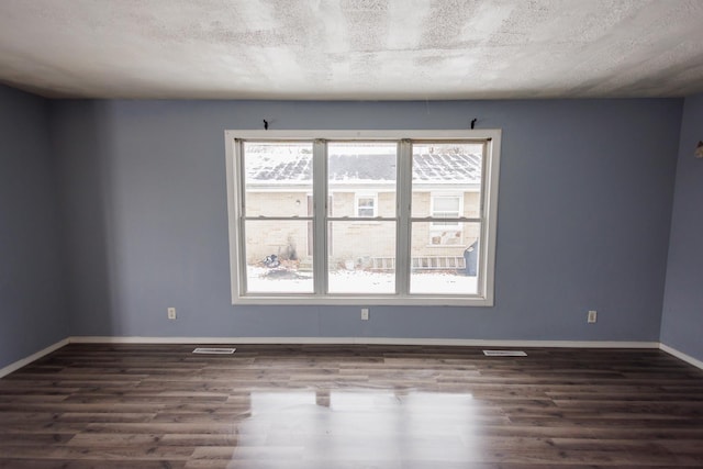 spare room featuring a textured ceiling, dark hardwood / wood-style floors, and a wealth of natural light