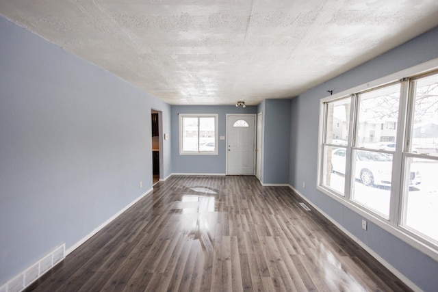 unfurnished living room with dark wood-type flooring and a textured ceiling