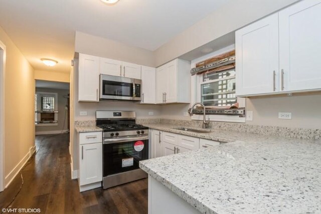 kitchen with kitchen peninsula, stove, light stone counters, dark wood-type flooring, and white cabinets