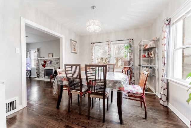 dining space featuring dark hardwood / wood-style flooring, an inviting chandelier, and a wealth of natural light