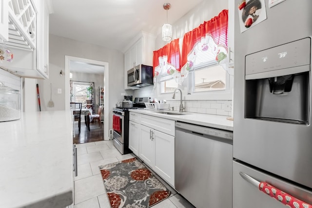 kitchen with white cabinets, light tile patterned floors, stainless steel appliances, and sink