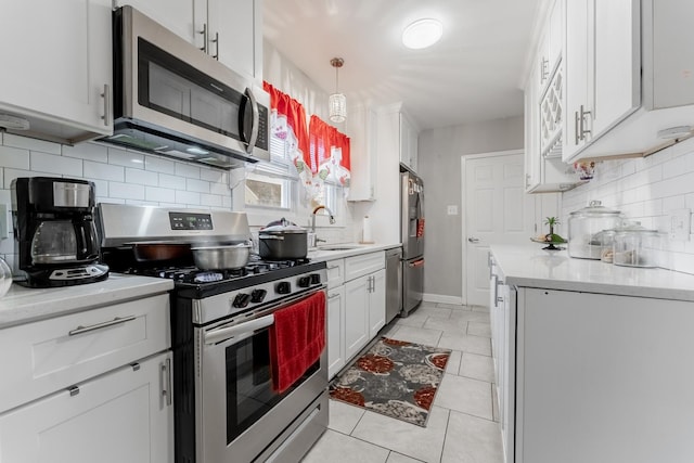 kitchen featuring white cabinets, decorative light fixtures, stainless steel appliances, and sink